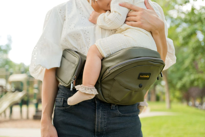 Parent carrying a baby on the Tushbaby Hip Carrier
