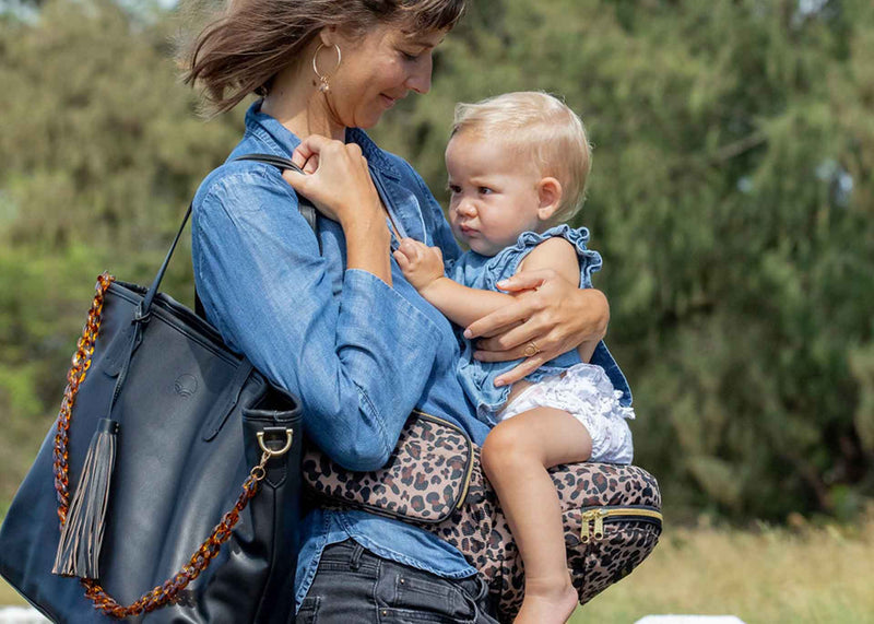 Parent holding baby outdoors, both wearing denim outfits, showing close bonding and travel-ready comfort.