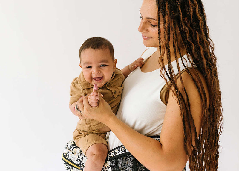 Smiling baby held by parent, sharing a joyful moment together.