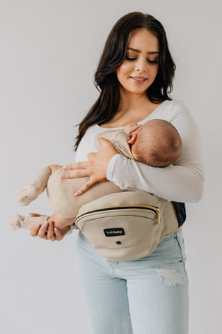 Parent using Tushbaby Hip Carrier to comfortably nurse baby in a cradle position.