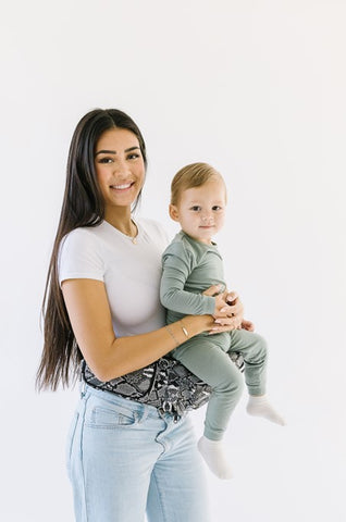 Parent carrying toddler in a front-facing position using a Tushbaby Hip Carrier, showing secure support and comfort for both.